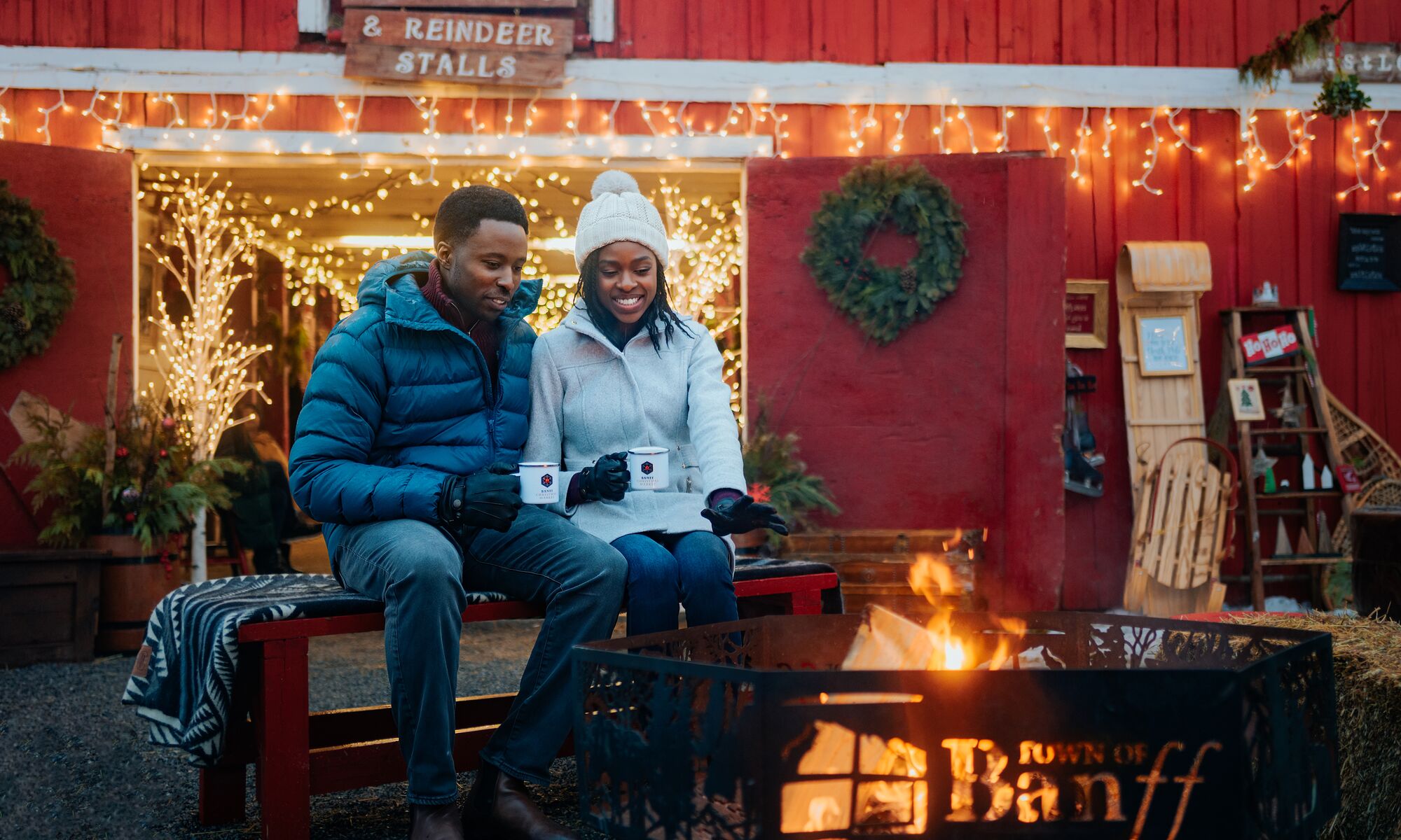 A couple sits at a campfire at the Banff Christmas Market.